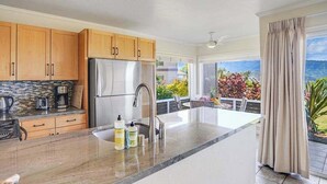 Eine moderne Küche mit einem Edelstahl-Kühlschrank, Holzschränken und einer großen Kochinsel mit Spüle.