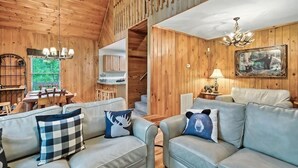 Un interior de madera con un conjunto de sofás, una zona de comedor y una escalera.
