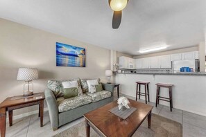 A living room with a sofa, coffee table, and a painting on the wall. - *New* Oceanfront Sunrise Retreat on Kauai's Coconut Coast (Kapaa)