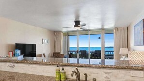 A kitchen with a large window, a ceiling fan, and a view of the ocean. - *New* Oceanfront Sunrise Retreat on Kauai's Coconut Coast (Kapaa)