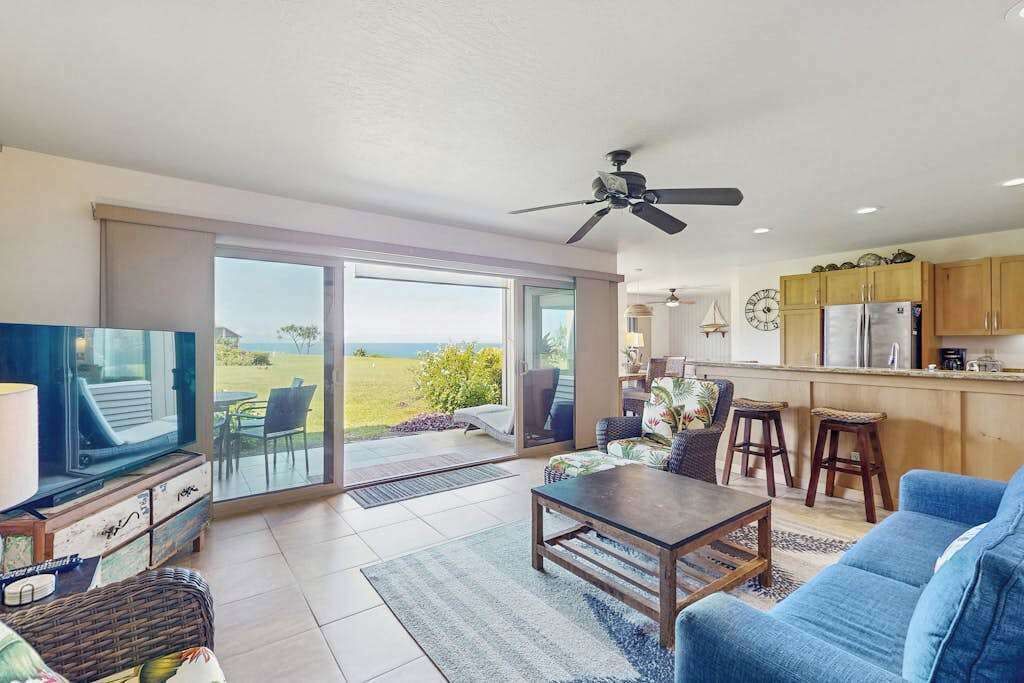 A spacious living area with a television, a sofa, a coffee table, and a view of the outdoors.