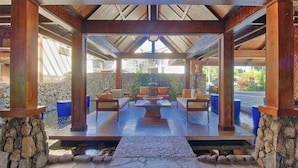 A covered outdoor seating area with stone pillars, a wooden deck, and a view of the surrounding landscape. - *New* Fall Special Top-Floor Bali Hai Views, Just Eight Steps Up (Princeville)