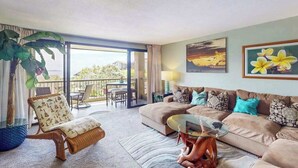 A living room with a sofa, armchair, and a glass coffee table. There is a balcony with a view of the outdoors. - NEW Bali Hai Views Above a Quiet Resort Pool (Princeville)