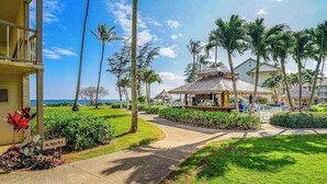 Um resort com uma passagem que leva a um edifício, palmeiras e vista para o oceano.