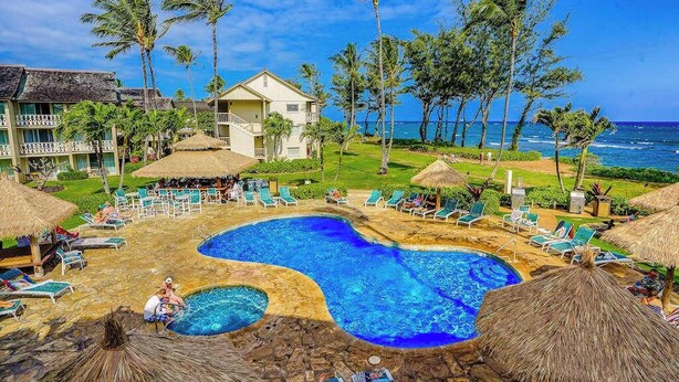 Um resort com piscina, espreguiçadeiras e vista para o oceano.