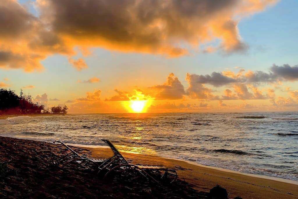 A sunset over the ocean with a beach in the foreground.