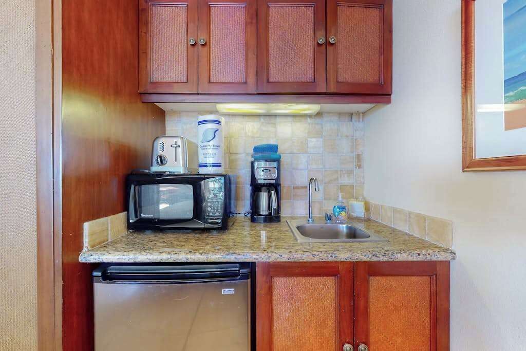 A compact kitchenette with a microwave, toaster, coffee maker, and a small sink.