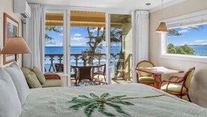 Habitación de hotel con cama, balcón con mesa y sillas, y vista al mar.