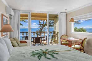 Ein Hotelzimmer mit Bett, einem Balkon mit Tisch und Stühlen und Blick aufs Meer.