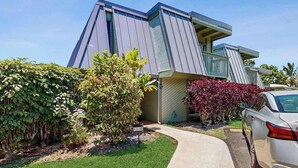 A modern two-story house with a sloped roof, a driveway, and a parked car. - NEW Fall Sale Ground-Floor Princeville Retreat with Pool and Lanais (Princeville)