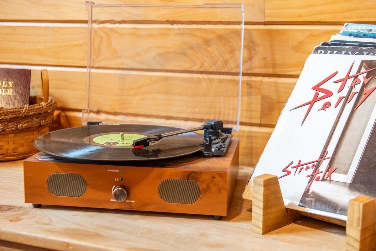 A wooden record player with a vinyl record on it, a speaker, and a framed album cover on a wooden surface.