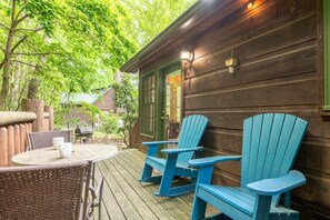 A wooden cabin with a porch, two Adirondack chairs, a table with two white mugs, and a green door. - Lazy Bear Lodge (Sevierville)