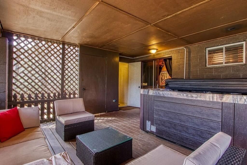 Un espace extérieur aménagé, abrité et doté d’un jacuzzi, d’une terrasse en bois et d’un treillis décoratif.