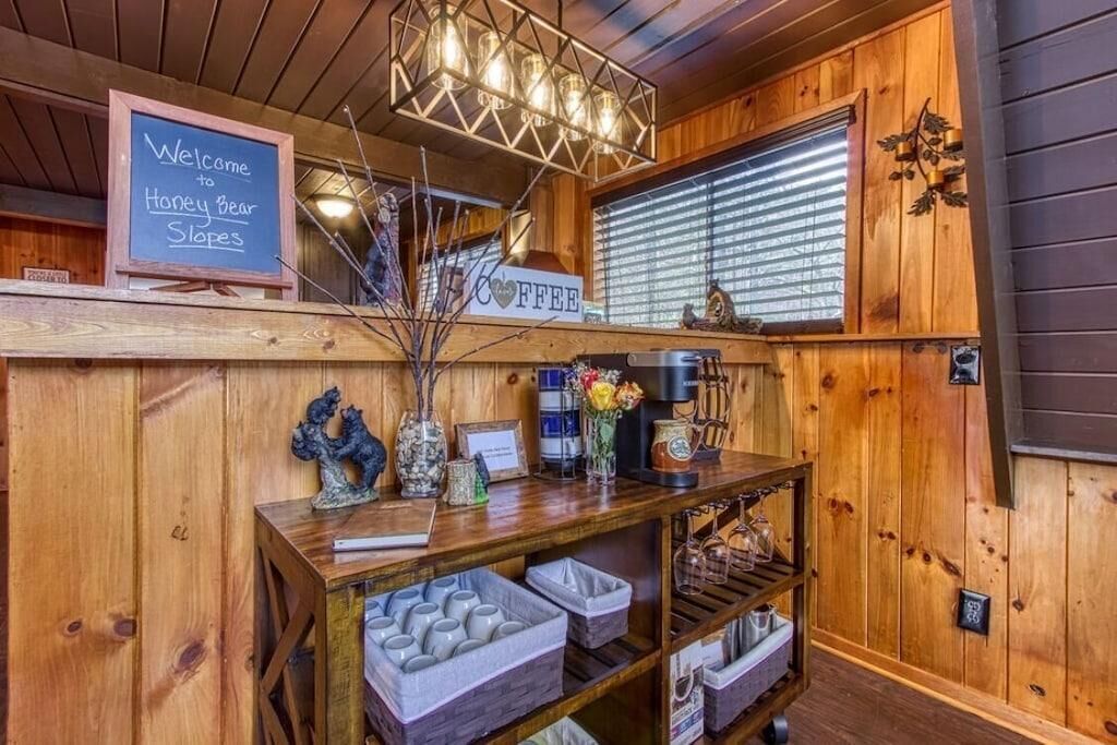 Een houten interieur met een schoolbord waarop staat 'Welcome to Honey Bear Slopes', een bordje voor koffie en een plank met potten en een decoratieve vos.