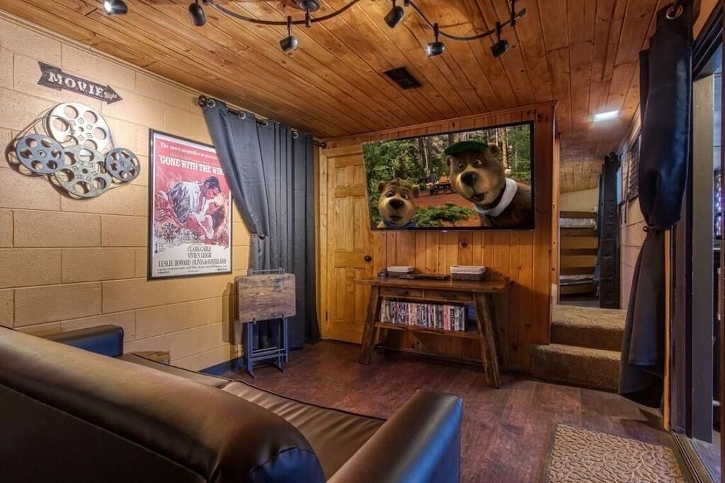 Um quarto acolhedor com teto de madeira, televisão montada, um cartaz e uma estante de livros.