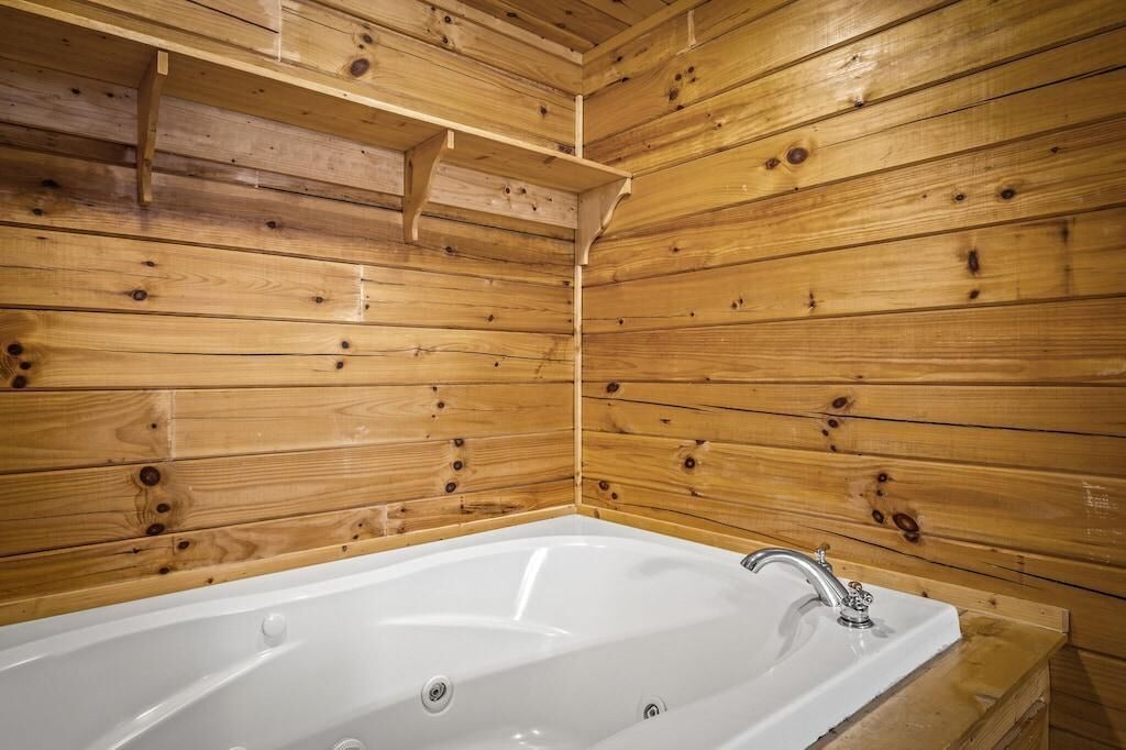 A wooden cabin interior with a white bathtub and a wooden shelf.
