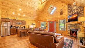 A log cabin interior with a kitchen, living area, and fireplace. - Mimi and Pop's Place (Gatlinburg)