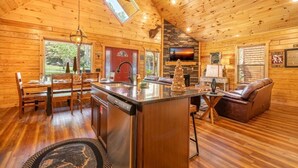A wooden cabin interior with a dining area, kitchen, and living space. - Mimi and Pop's Place (Gatlinburg)