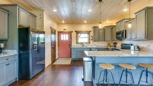 A kitchen with wooden ceiling, stainless steel appliances, granite countertops, and bar stools. - Misty Mountain Stop (Sevierville)