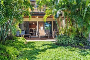 A house with a covered patio, surrounded by lush greenery and palm trees. - NEW Fall Special Ground-Floor Kihei Garden Condo Near Kamaole III (Kihei)