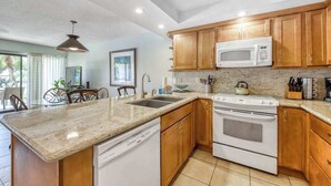 Una cocina con gabinetes de madera, un microondas, una estufa y un lavavajillas.