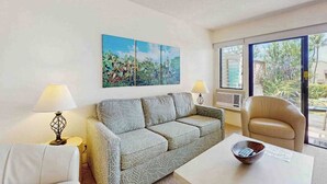 A living room with a sofa, a chair, a coffee table, and a painting on the wall. - *New* Fall Special Garden-View 1BR Kihei Condo Near Kamaole III (Kihei)