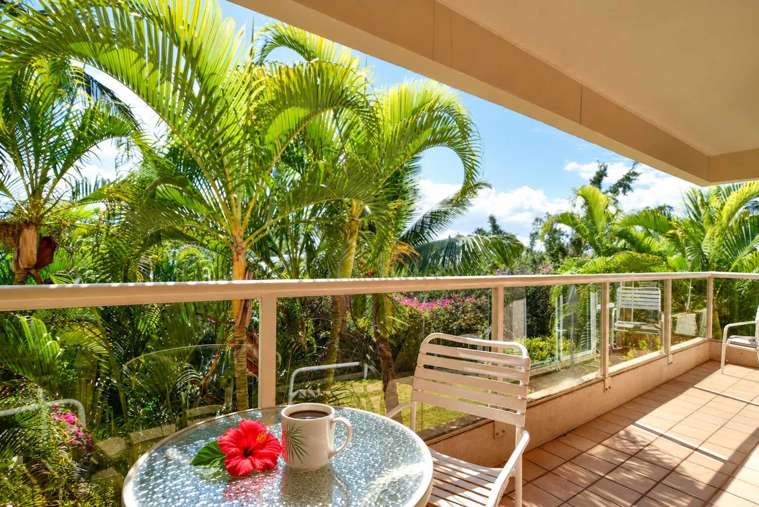 A balcony with a glass table, a chair, and a potted plant.