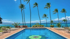 A swimming pool with a tropical view, palm trees, and a clear sky. - *NEW* Turtle-Watching Oceanfront Lanai in West Maui (Lahaina)