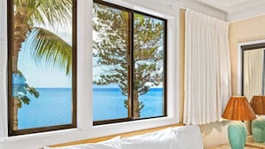 A room with a bed, a window with a view of the sea, and a lamp on a nightstand. - *NEW* Turtle-Watching Oceanfront Lanai in West Maui (Lahaina)
