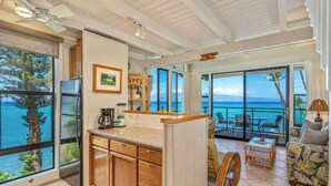 A kitchen with a view of the ocean, a dining area with a table and chairs, and a living area with a sofa and a view of the ocean. - *NEW* Turtle-Watching Oceanfront Lanai in West Maui (Lahaina)