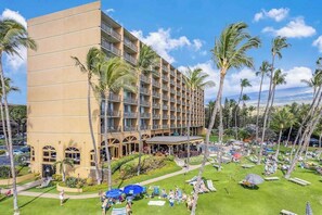 Un hôtel à plusieurs étages, doté d’une piscine extérieure et bordé de palmiers.