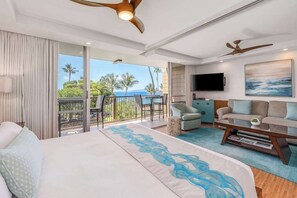 Une chambre d’hôtel avec un lit, un canapé, une télévision et un balcon donnant sur l’océan.