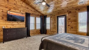 Una stanza con rivestimento in legno, un letto, un comò e un televisore appeso al muro.