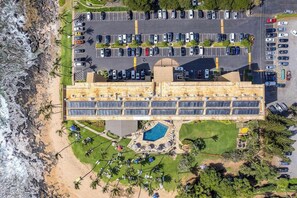 Um edifício grande com estacionamento, piscina e vista para a praia.