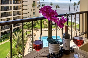 A balcony with a view of a pool, a bottle of wine, and two glasses of red wine. - NEW Ocean-View Sugar Beach Penthouse for Four in Kihei (Kihei)