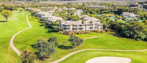 Um campo de golfe com um clube e edifícios residenciais.
