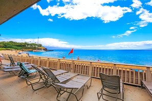 Un patio frente a la playa con sillones de descanso y vista al océano.