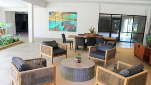 A modern lobby with wicker furniture, a round coffee table, and a large abstract painting. - NEW Fall $ale Third-Floor Kahana Sunsets and Ocean Views Near Ka'anapali (Lahaina)