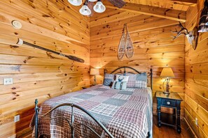 Ein Holzhütten-Zimmer mit einem Bett, einem Nachttisch, einer Lampe und Wanddekoration.