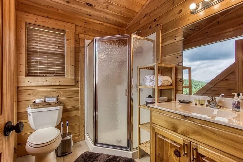 Bany d'una cabana de fusta amb vàter, dutxa i tocador.