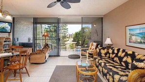 Un salon comprenant un canapé, des fauteuils, une table basse, un téléviseur et un ventilateur de plafond.