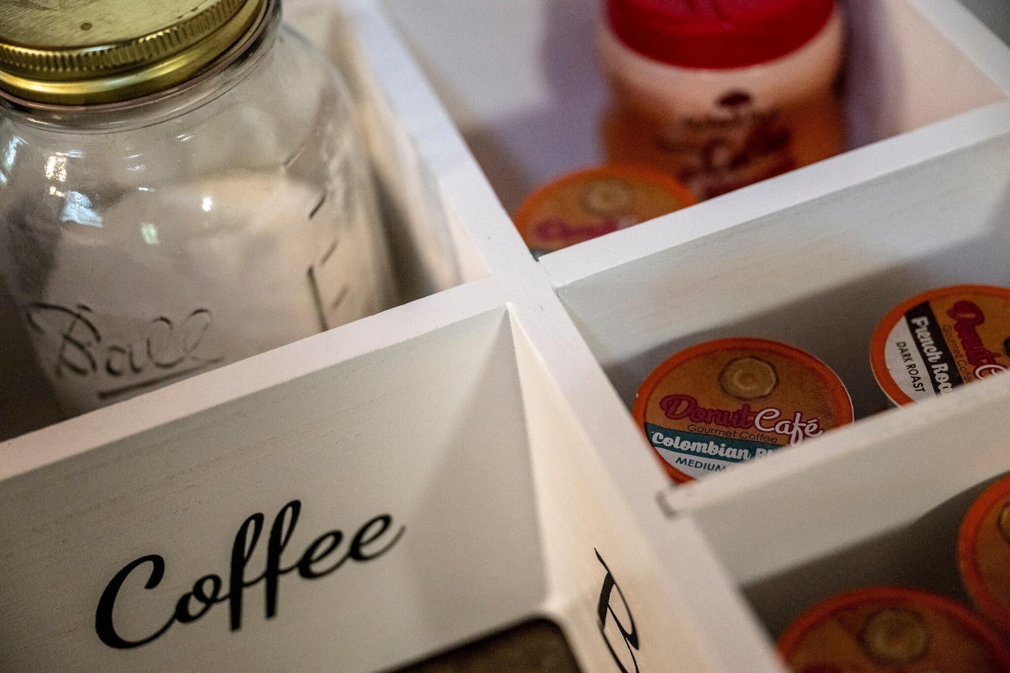 A storage area with labeled compartments for coffee and a jar labeled 'Ball'.