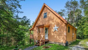 Uma cabana de madeira com varanda, decoração de estrela e um pequeno deck.