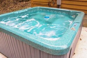 Ein Whirlpool mit blauer Abdeckung, einer Steuerung und einer Holzverkleidung im Hintergrund.