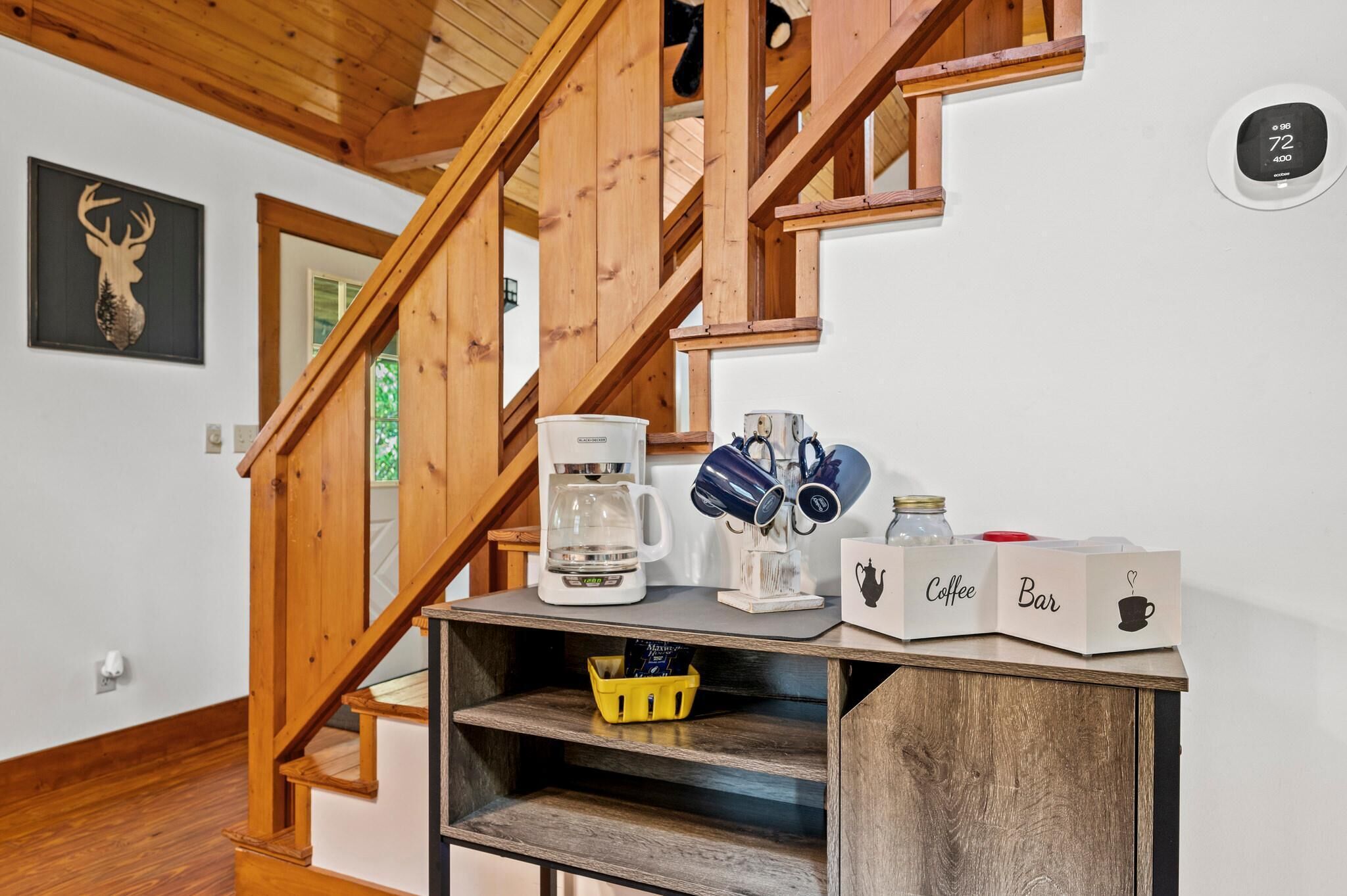A wooden staircase, a coffee maker, mugs, and labeled boxes on a shelf.