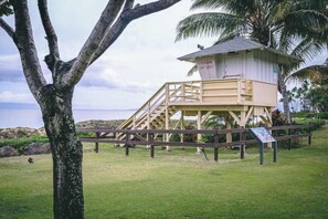 A lifeguard tower with a wooden staircase, surrounded by grass and palm trees. - *New* Fall Sale Ocean Views Across from Kamaole Beach II (Kihei)