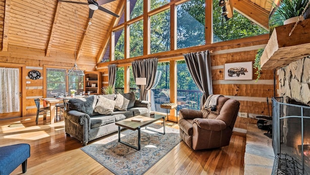 A spacious wooden cabin with a high ceiling, large windows, a fireplace, and a cozy seating area. - Second Fiddle (Sevierville)