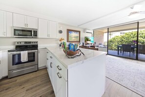 A modern kitchen with built-in appliances, a dining area with a view, and a balcony. - *New* Fall $pecial Ocean-View Kihei Escape Across from the Beach (Kihei)