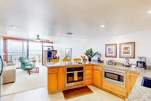 A modern kitchen with granite countertops, wooden cabinets, and stainless steel appliances. - NEW Oceanfront Kahana Retreat With Heated Pool and Lanai (Lahaina)
