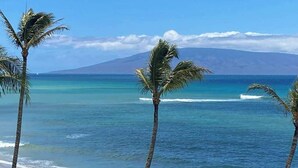 A beach with clear blue water, palm trees, and a mountain in the background. - NEW Fall Sale Fifth Floor Kahana Oceanfront with Two Lanais (Lahaina)